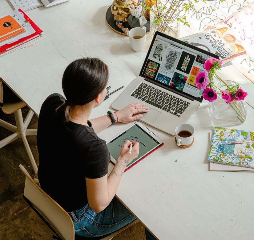 A designer working on a laptop and iPad